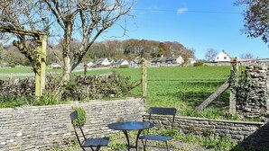 A stone wall, a metal table with two chairs, and a view of houses in the background. - 2 bedroom accommodation in Levens, near Kendal (Levens, near Kendal)