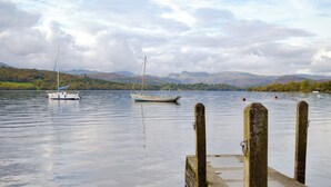 A calm lake with a dock and two sailboats.