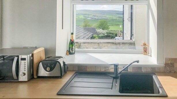 A kitchen with a window view, a toaster, a kettle, and a bottle of champagne.