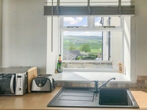 Una cocina con vistas por la ventana, un tostador, una tetera y una botella de champán.