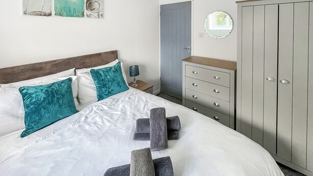 A neatly arranged bedroom with a bed, a dresser, a wardrobe, and a nightstand. - 2 bedroom accommodation in Levens, near Kendal (Levens, near Kendal)