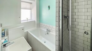 A bathroom with a bathtub, a shower, and a window.