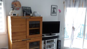 A living room with a wooden cabinet, a television, and a glass door leading outside. - Arzon au balcon - Port du Crouesty (Arzon)