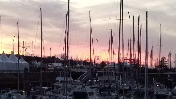 A marina with multiple boats docked, a calm water surface, and a sunset in the background. - Arzon au balcon - Port du Crouesty (Arzon)