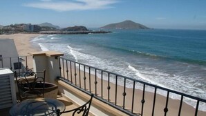 A balcony with a view of the ocean, a sandy beach, and distant hills. - Condos Tiara (Mazatlán)