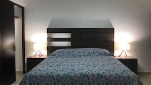 A bedroom with a bed, two bedside tables, and a headboard with built-in lighting. - Depas Veleros (Mazatlán)
