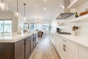 A modern kitchen with a central island, pendant lighting, and a view to the dining area.