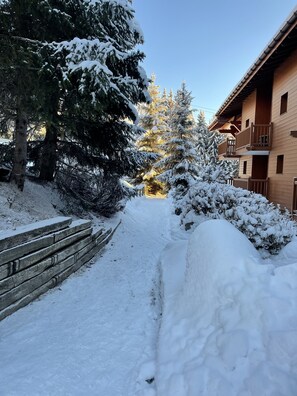 A snow-covered pathway leading to a wooden building with balconies. - ARCS 1800 COSY SKI-IN/SKI-OUT APARTMENT IN A LUXURY CHALET (Bourg Saint Maurice)