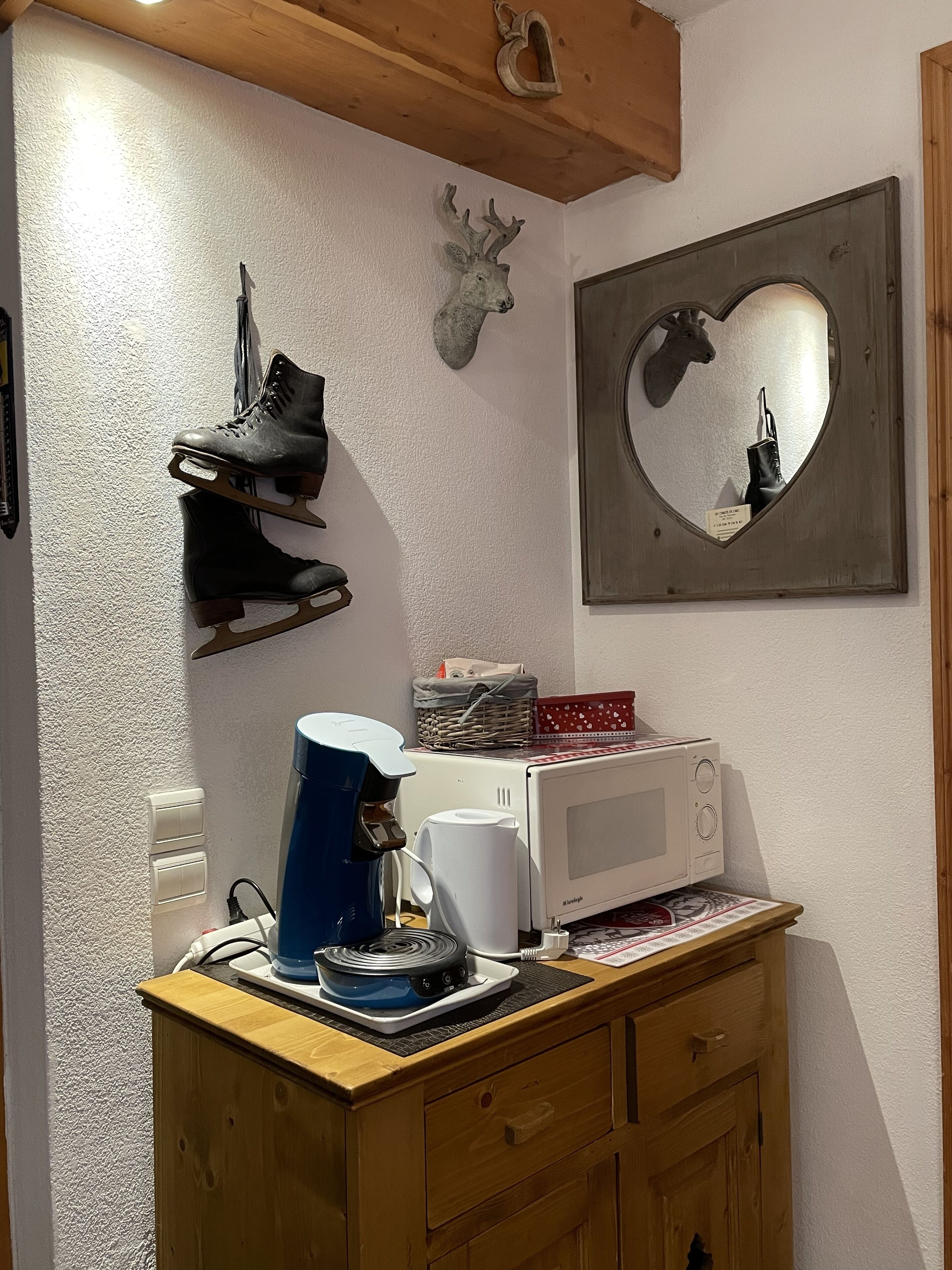 Une cuisine équipée d’un four à micro-ondes, d’une machine à café et d’un miroir en forme de cœur accroché au mur.