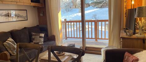 A cozy living room with a wooden floor, a sofa, a coffee table, and a television.