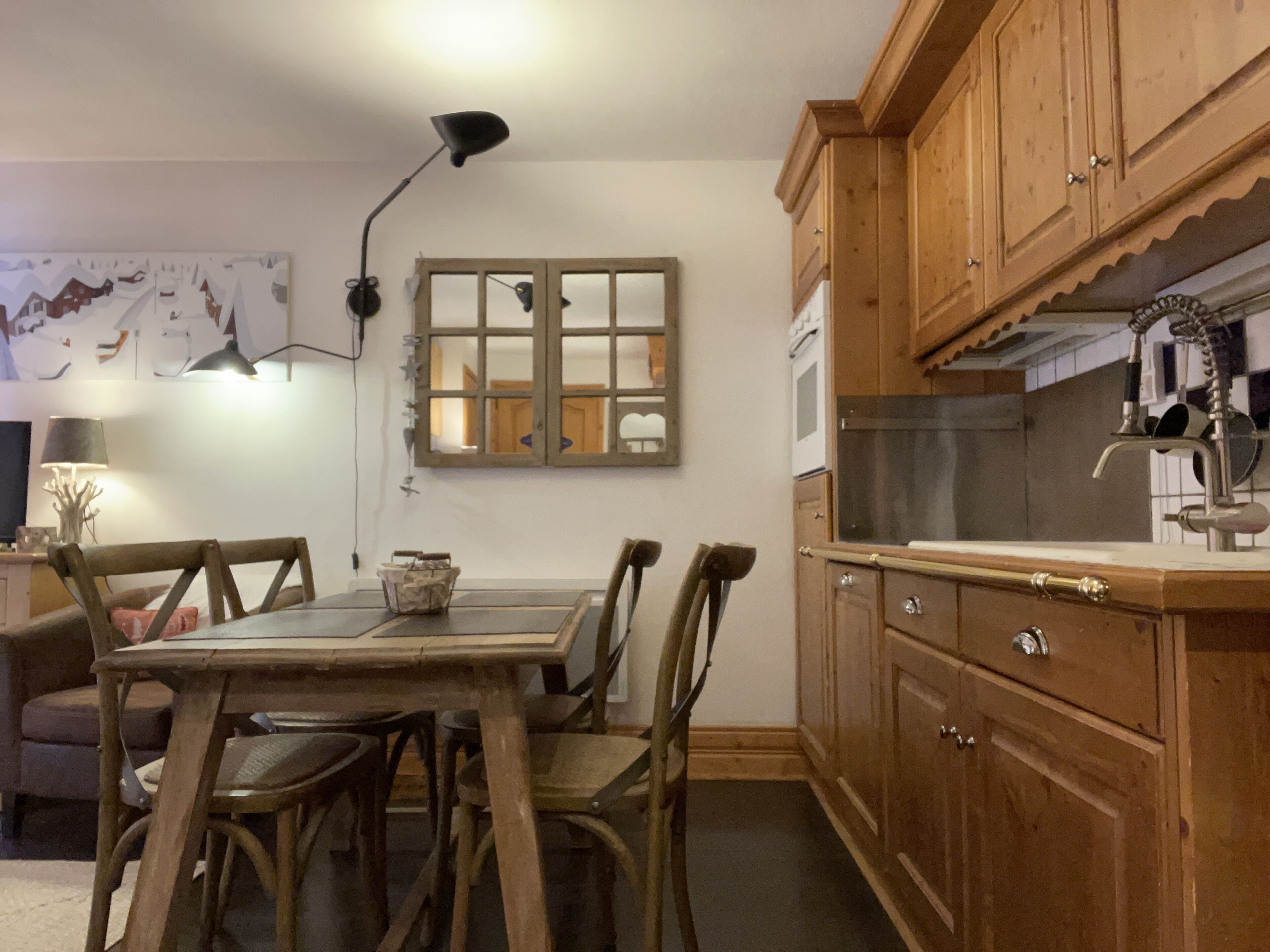 Una cucina con mobili in legno, un tavolo da pranzo con sedie, una finestra con vista e una lampada.