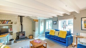 A cozy living room with a blue sofa, a wooden coffee table, a fireplace, and a bookshelf. - 3 bedroom accommodation in Kettleness, near Whitby (Kettleness, near Whitby)