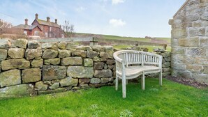 A stone wall with a wooden bench in a grassy area. - 3 bedroom accommodation in Kettleness, near Whitby (Kettleness, near Whitby)