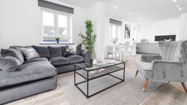 A modern living room with a grey sofa, a glass coffee table, and a grey armchair. - The Marsons Collection- 2 Bed Apartment- Parking (Birmingham)