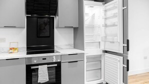 A modern kitchen with a built-in oven, a microwave, and a refrigerator with multiple shelves. - The Marsons Collection- 2 Bed Apartment- Parking (Birmingham)