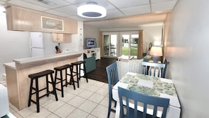 A compact kitchen with a bar area, a dining table with chairs, and a view of the outdoor area. - Beach Chairs For 4 • 1st Floor • Sleeps 6 (Panama City Beach)