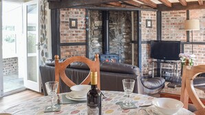 Una sala de estar acogedora con chimenea, sofá de cuero y comedor listo con platos y vasos.