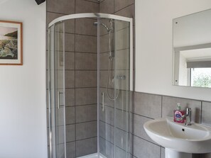 Ein modernes Badezimmer mit Duschkabine aus Glas, einem weißen Waschbecken und einem gerahmten Bild an der Wand.