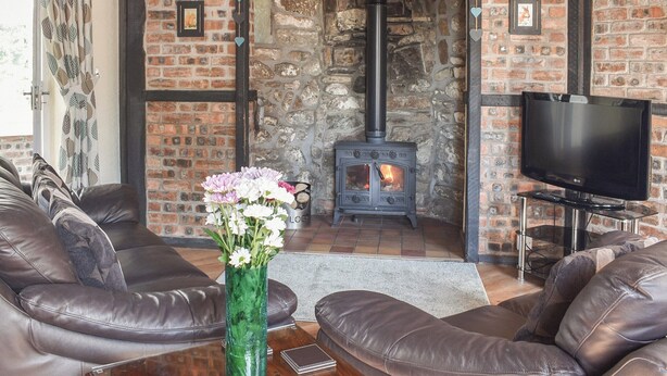 Una sala de estar acogedora con sofás de cuero, un televisor y una chimenea con pared de piedra.
