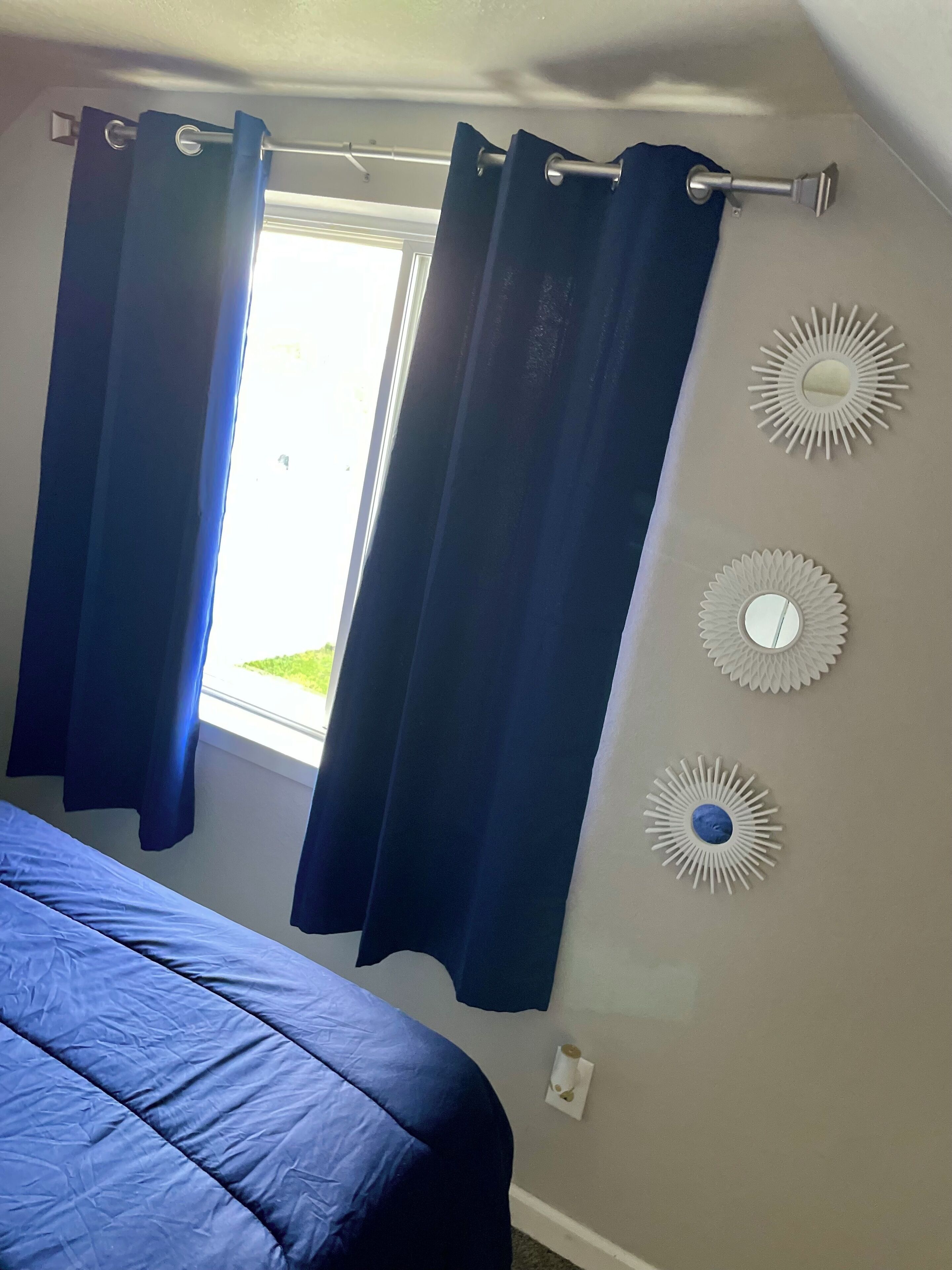A bedroom with a bed, curtains, and wall decor.