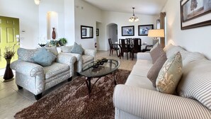A living room with two sofas, a coffee table, and a dining area with chairs and a table. - Serenity By Your Private Pool! Excellent Reviews! Resort Living! 4450 (Kissimmee)