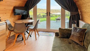 Une pièce chaleureuse avec un décor intérieur en bois, une table à manger avec des chaises, un canapé avec des coussins et un téléviseur.