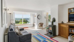 A living room with a sofa, a colorful rug, a fireplace, and a bookshelf. - Spacious Apartment in Rock, Private Parking (Rock)