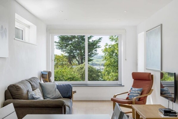 A modern living room with a large window, a sofa, a chair, and a flat-screen TV. - Spacious Apartment in Rock, Private Parking (Rock)