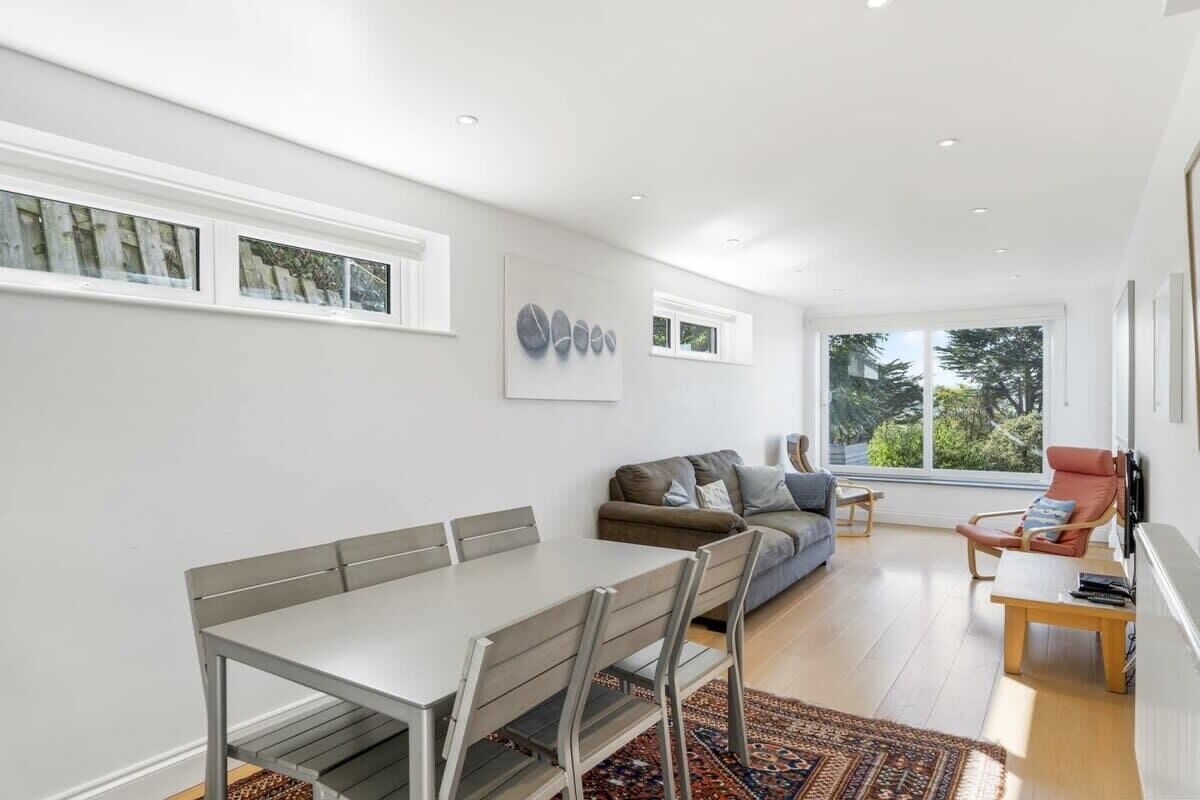 A modern living room with a dining table, sofa, and a large window.