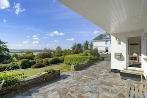 A stone-paved patio leading to a white building with a covered porch. - Spacious Apartment in Rock, Private Parking (Rock)
