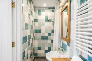 A bathroom with a tiled shower wall, a sink, and a mirror. - Spacious Apartment in Rock, Private Parking (Rock)