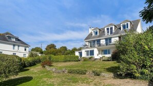 A two-story house with a large front lawn, a balcony on the upper floor, and a satellite dish. - Spacious Apartment in Rock, Private Parking (Rock)