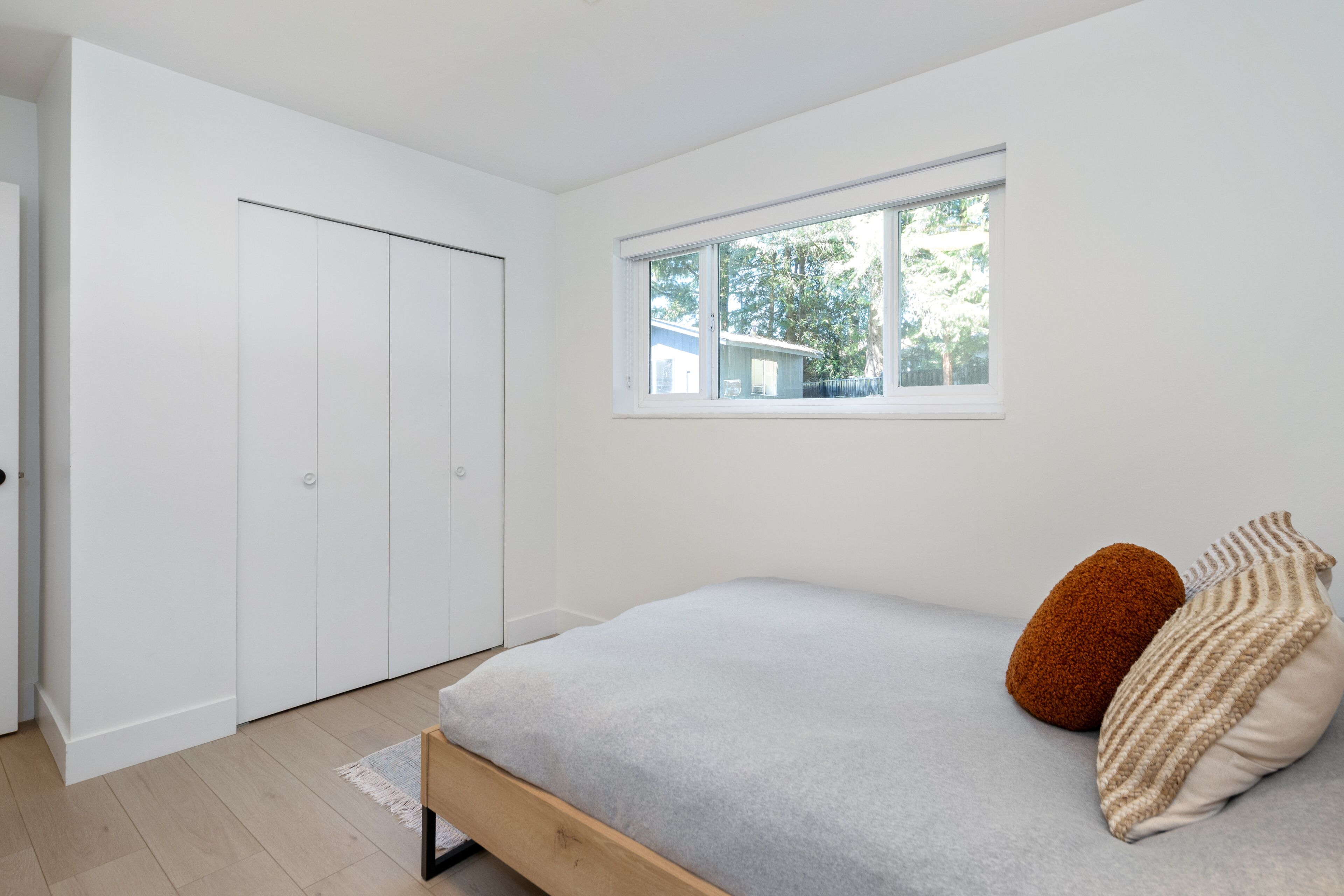Une chambre à coucher avec un lit, des oreillers, une fenêtre et une armoire.
