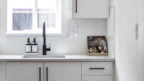 A modern kitchen with white cabinets, a black faucet, and a window above the sink.