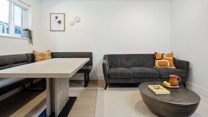 A modern living room with a dining table, two sofas, a coffee table, and a small decorative item on the wall.