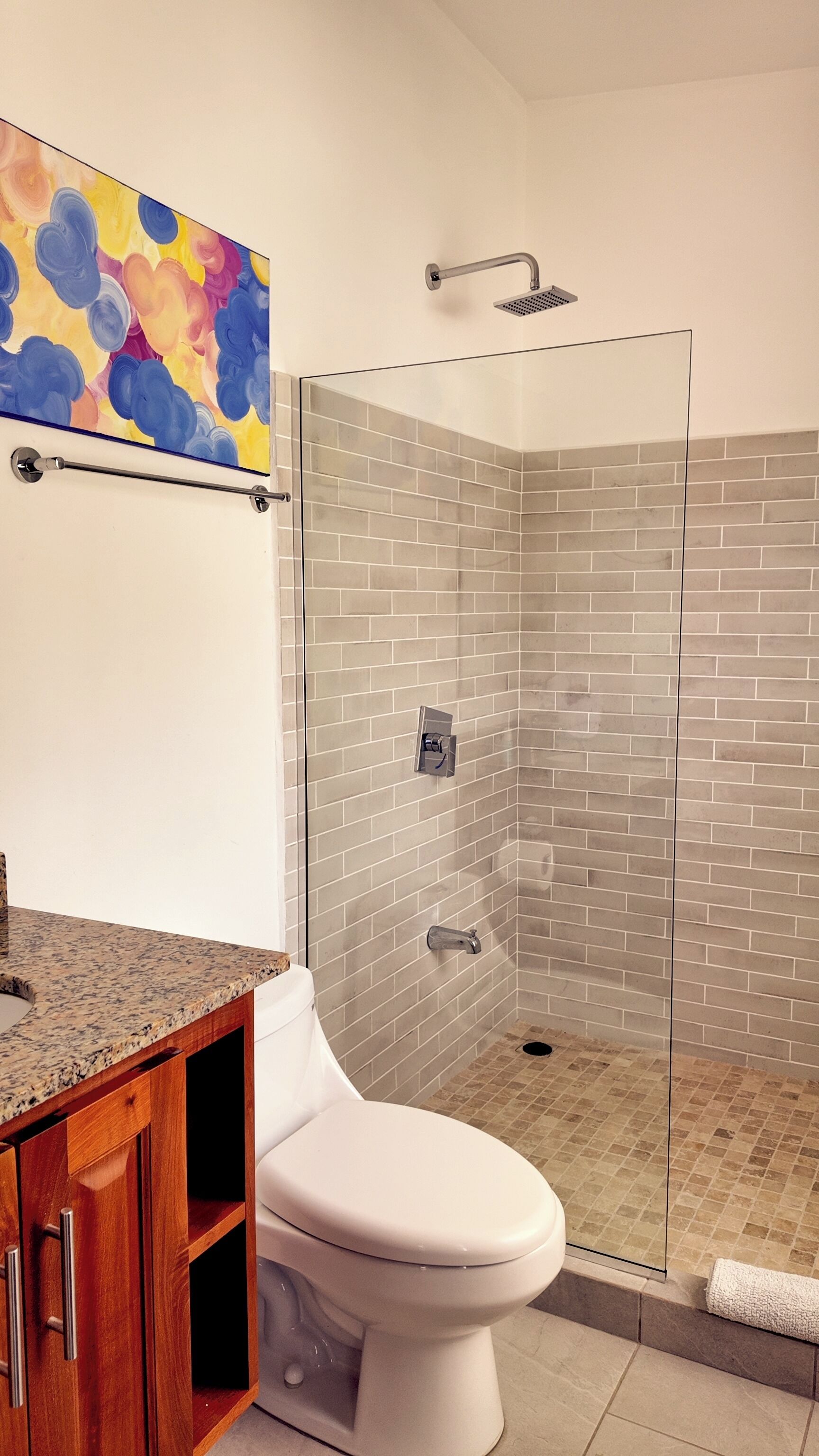 A bathroom with a shower, toilet, and a wooden cabinet.