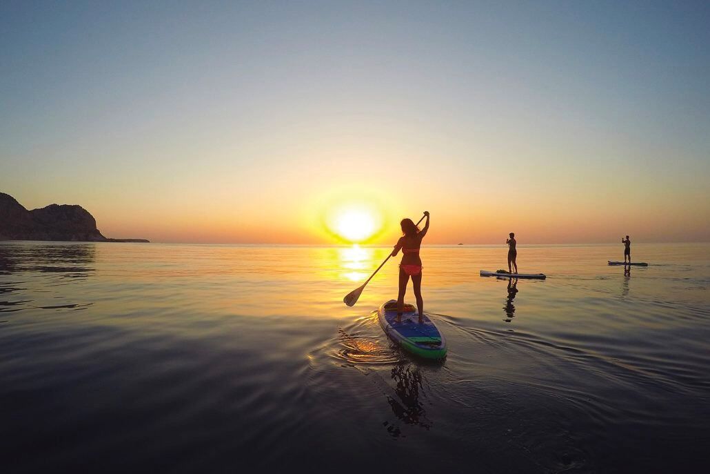 Een zonsondergang boven kalm water met paddleboards.