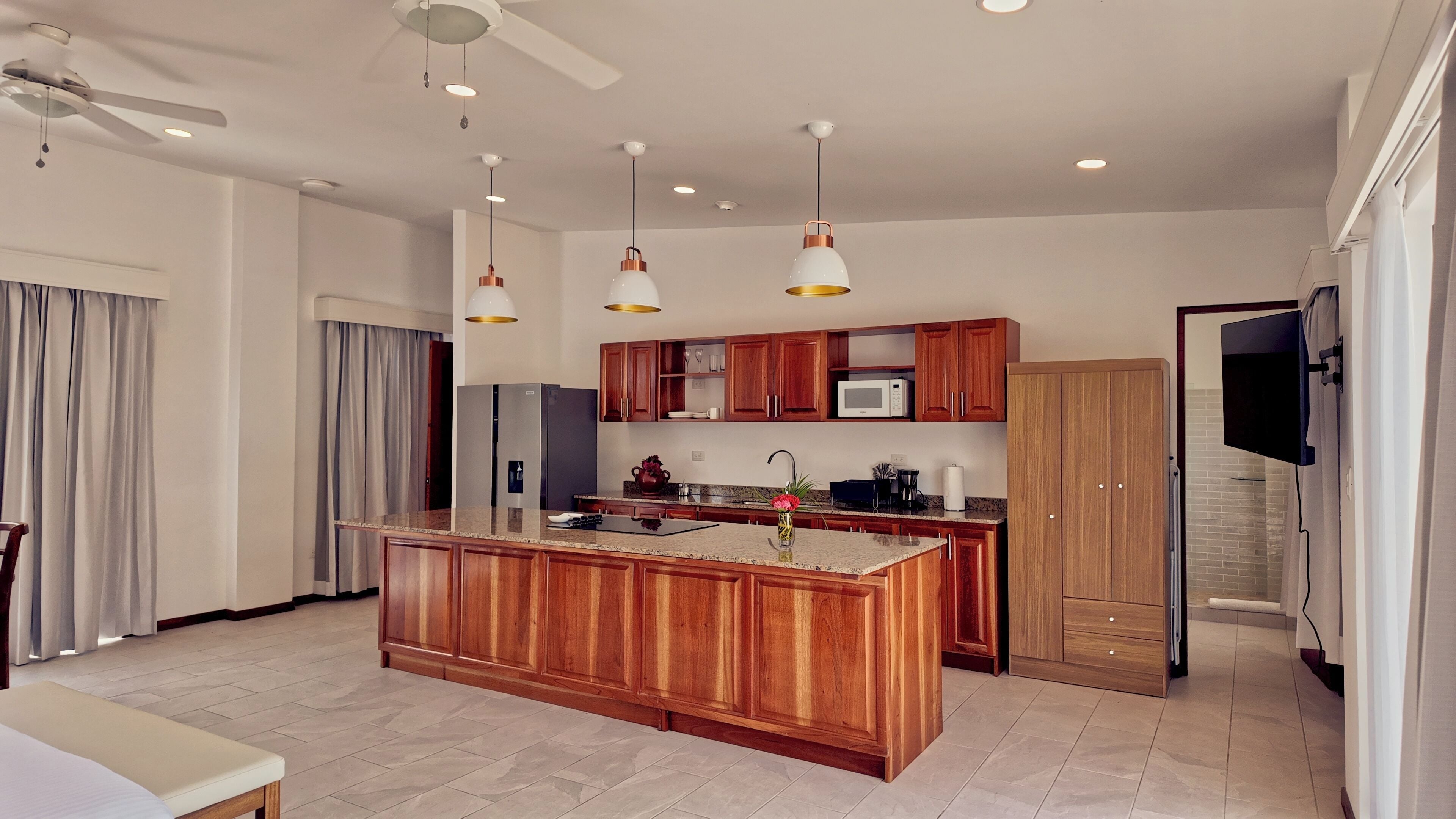 A modern kitchen with wooden cabinets, a central island, and pendant lighting.