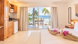 Habitación de hotel con cama, banco, kitchenette y vista a la playa.