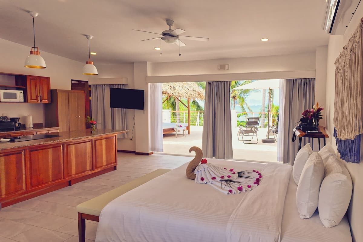 A hotel room with a bed, a kitchenette, a TV, and a view of the outdoors.