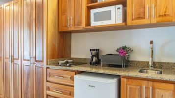 A kitchen with wooden cabinets, a microwave, a coffee maker, and a small refrigerator.