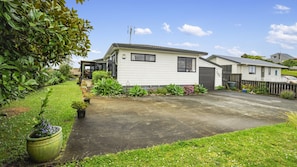A single-story mobile home with a paved driveway, surrounded by a well-maintained garden with various plants and flowers.