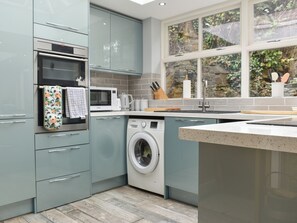 A modern kitchen with grey cabinets, a built-in oven, microwave, and washing machine. - 3 bedroom accommodation in Chesterfield (Chesterfield)