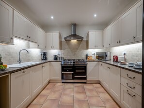 A modern kitchen with white cabinets, a gas stove, a microwave, and a sink.