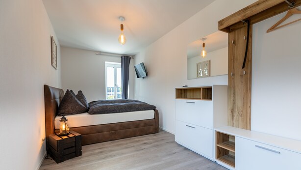 Un dormitorio moderno con cama, mesita de noche y armario.