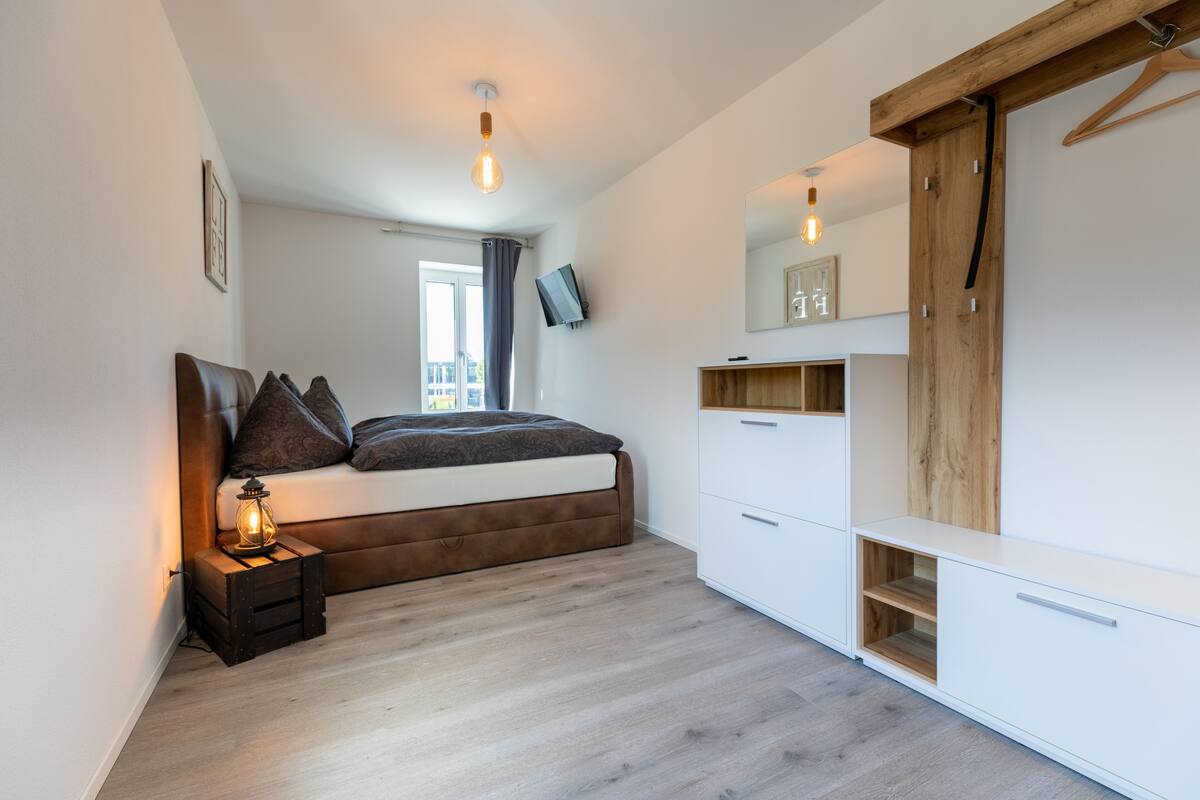 A modern bedroom with a bed, bedside table, and wardrobe.