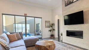 A modern living room with a sofa, a coffee table, and a flat-screen TV mounted on the wall. - Almanzo: Private Pool + Golf + Sand Dunes (Hurricane)