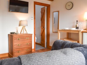 Une chambre à coucher avec un lit, une commode en bois, une table de chevet, une lampe et une horloge au mur.