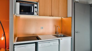 Une petite cuisine équipée d’un four à micro-ondes, d’un évier et d’un lave-vaisselle.