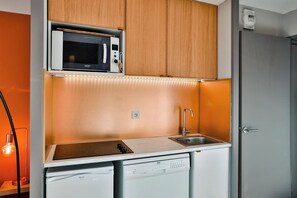 Une petite cuisine équipée d’un four à micro-ondes, d’un évier et d’un lave-vaisselle.
